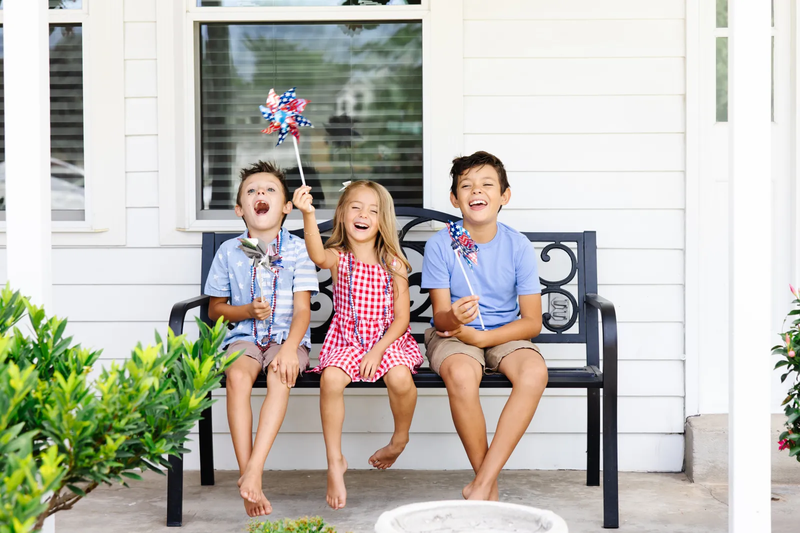 kids on a bench outside a white home