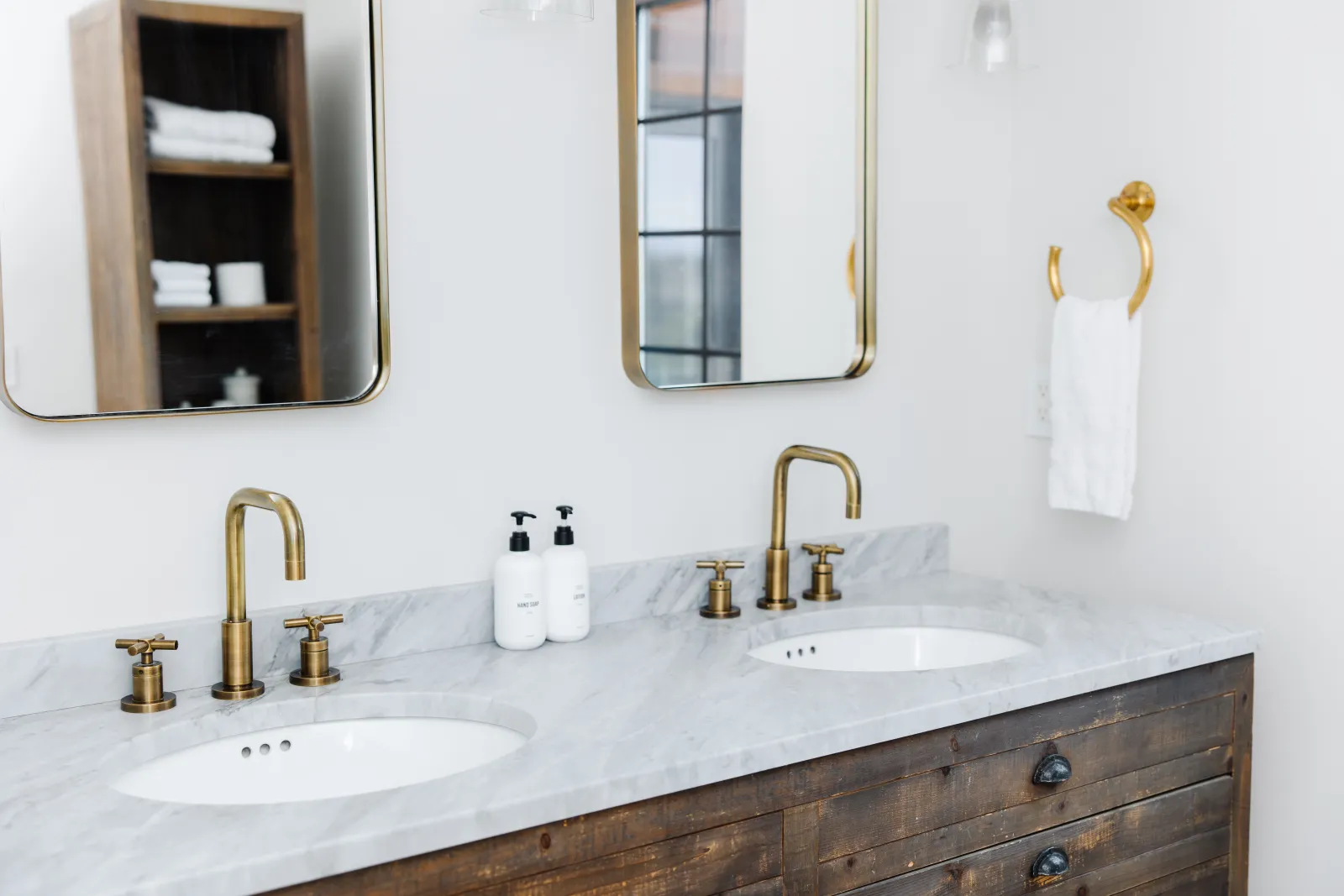 Double white bathroom vanity sink area with gold accent fixtures