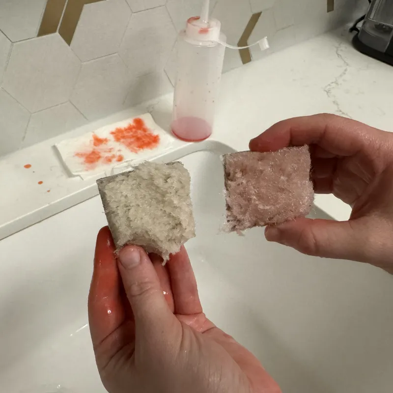 a pair of hands holding a piece of bread on a cutting board